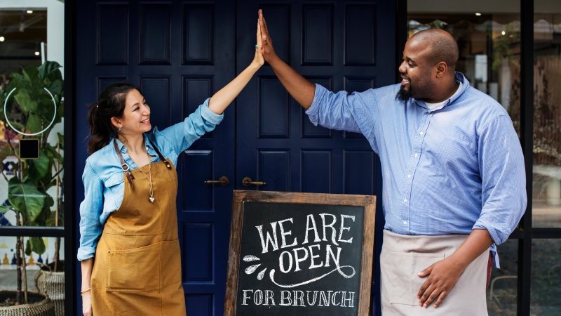 couple opening shop high fiving