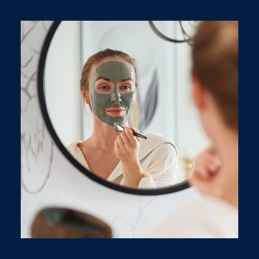Woman applying a face mask in the mirror