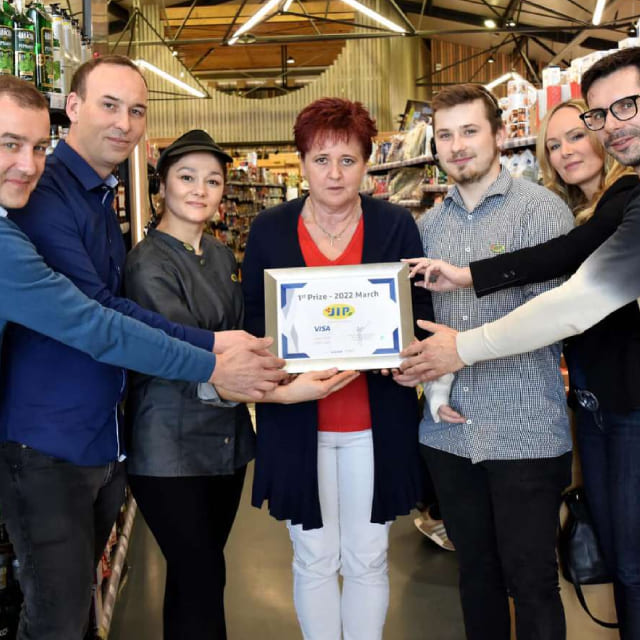 Seven people hold the winner's plaque for March from VISA