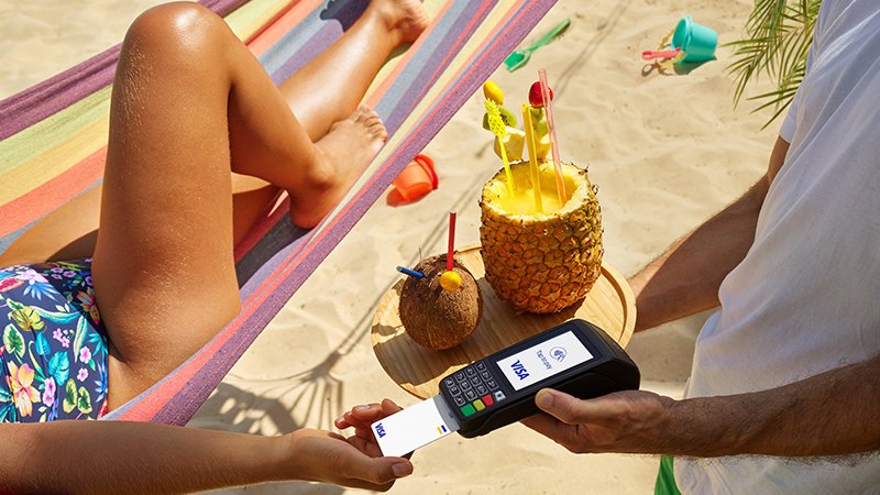 woman making card payment whilst sunbathing on beach